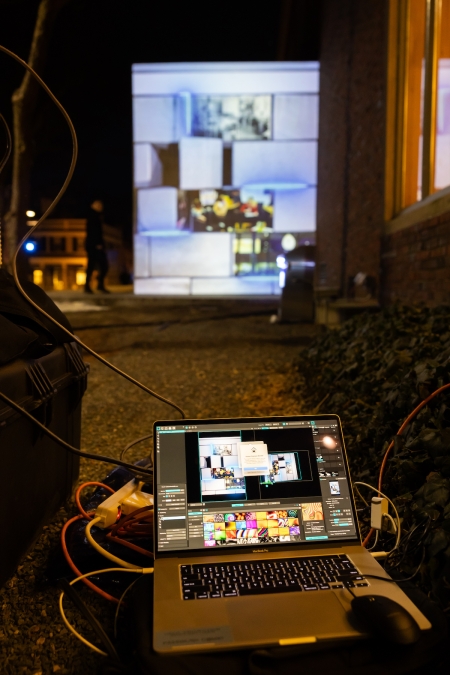 A computer in front of a wall projection